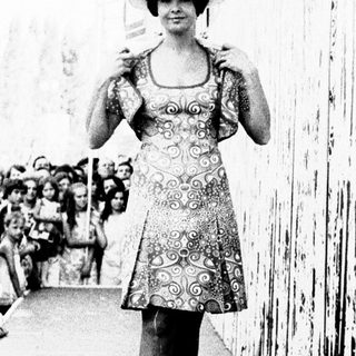 Model walks down runway in vintage dress.