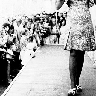 Model walks down runway in vintage dress.