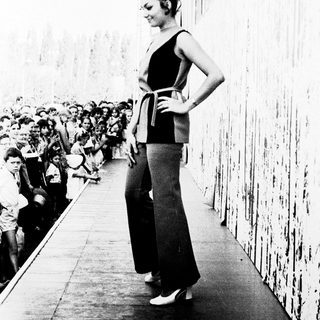 Woman posing confidently on runway during fashion show.