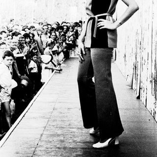 Woman posing confidently on runway during fashion show.