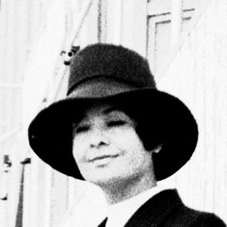 Elegant woman in 1940s attire posing outdoors.