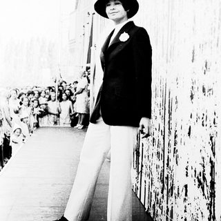 Elegant woman in 1940s attire posing outdoors.