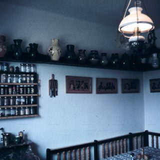 Vintage kitchen with ceramic jars, shelves, and rustic decor.