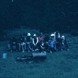 Group camping around a fire at night.