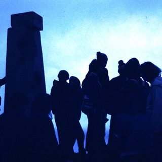 People gathered around a tall monument at dusk.