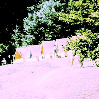 Campsite with tents on grassy hillside.