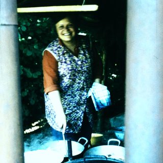 Woman smiling while cooking outdoors with pots.