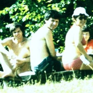 People relaxing outdoors near camping tent.