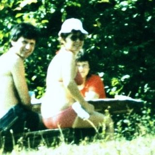 People relaxing outdoors near camping tent.