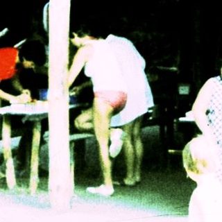 Outdoor picnic area with people gathered under shelter.