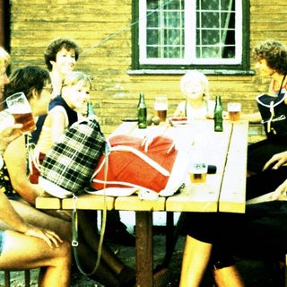 Group socializing outdoors at rustic wooden building.