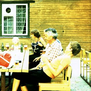 Group socializing outdoors at rustic wooden building.