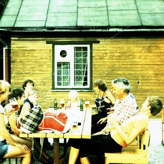 Group socializing outdoors at rustic wooden building.