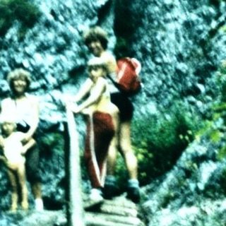People hiking near a waterfall in a lush forest.