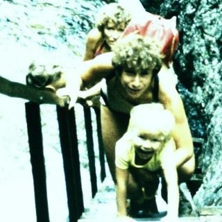People climbing stairs near cascading waterfall.