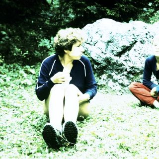 Four people sitting outdoors near rocks.