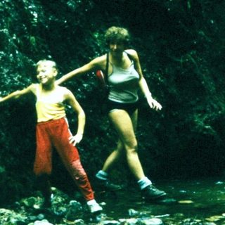 People exploring waterfall in lush forest setting.