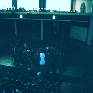 Large indoor audience watching a stage performance.