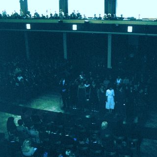 Large indoor audience watching a stage performance.
