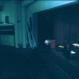 Empty lecture hall with stage and tables.