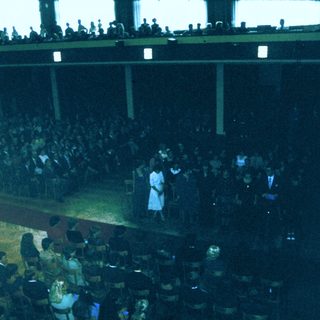 Graduation ceremony with students and graduates on stage.