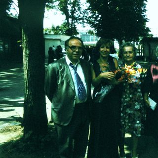 Group posing outdoors with floral bouquet.