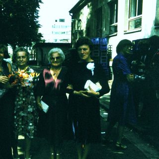 Group posing outdoors with floral bouquet.