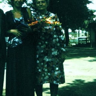 Group of people posing outdoors with floral wreath.