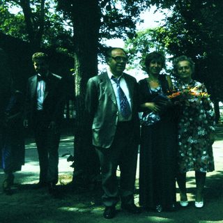 Group of people posing outdoors with floral wreath.
