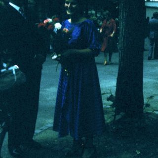 People holding flowers during outdoor ceremony.