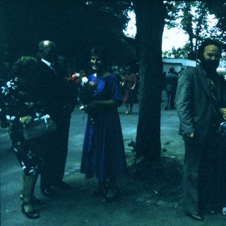 People holding flowers during outdoor ceremony.