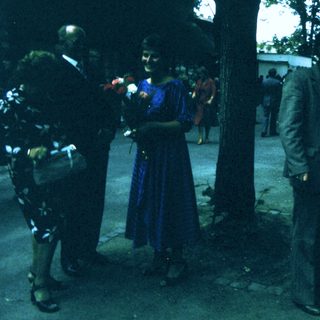 People holding flowers during outdoor ceremony.