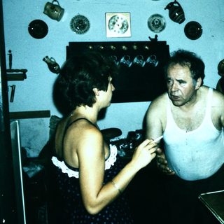 Shirtless man and woman in vintage indoor setting.