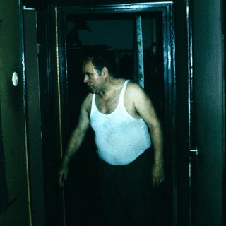Man exiting dimly lit shower area.