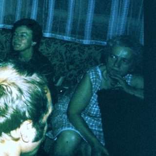 Group of people gathered indoors, playing video game.