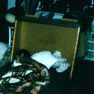 Family resting on hotel beds with luggage.