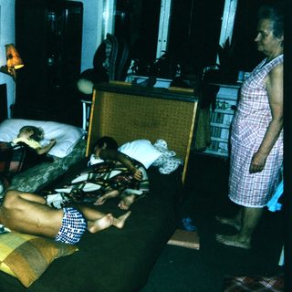 Family resting on hotel beds with luggage.