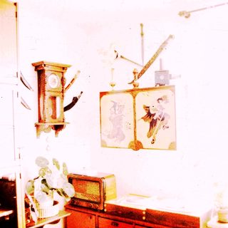 Vintage room with antique clock, wall art, and old furniture.
