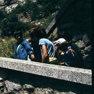 Historic stone tower on rocky cliff with visitors.