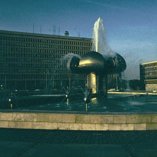 Modern fountain sculpture with water jets in urban plaza.