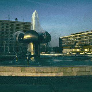 Modern fountain sculpture with water jets in urban plaza.