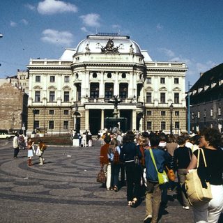 Grand neoclassical building in public square with pedestrians.