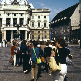 Grand neoclassical building in public square with pedestrians.