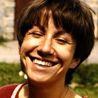 Woman smiling while holding wild mushrooms outdoors.