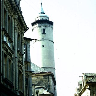 Historic tower rising above narrow European street.