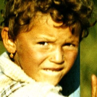 Boy clapping happily outdoors on grass.