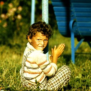 Boy clapping happily outdoors on grass.