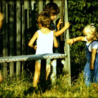 Three children playing near a fence.