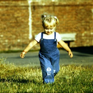 Young girl running in overgrown grass.