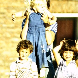 Five children playing on a swing set outdoors.